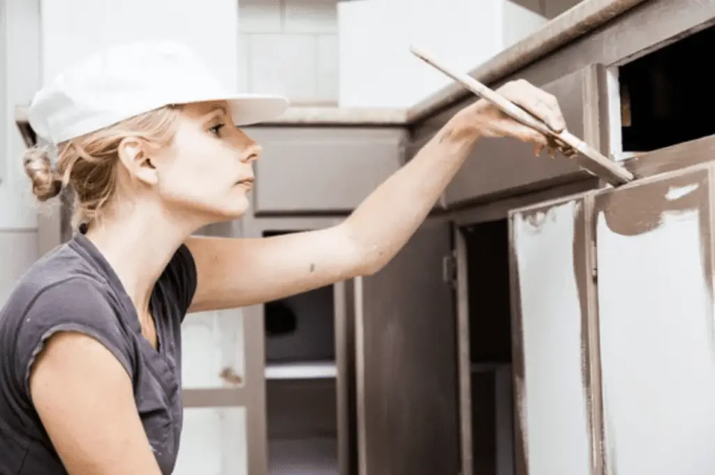 A woman paints the kitchen cabinet